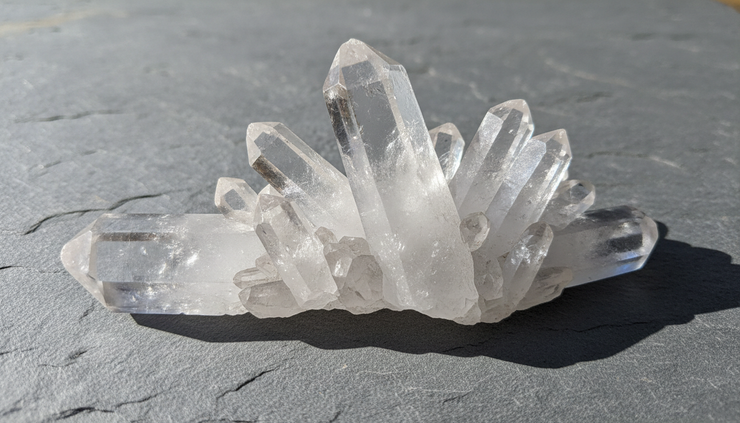 Close-up view of clear quartz crystals resting on natural stone.