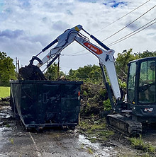 excavator loading dumpster at debris cleanup site in thomasville georgia