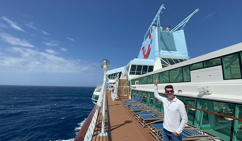 UK cruise content creator Tom pointing towards the distinctive wave-branded funnel from the top deck of the Marella Discovery cruise ship.