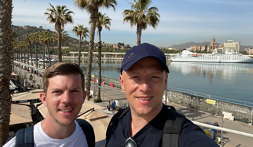 Tom and Dom Travel walking out of the Málaga cruise port terminal along the scenic harbour walkway towards the city centre.