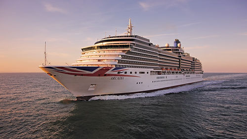 P&O Cruises ship Arcadia sailing on the open ocean at sunset with golden evening light on the water.