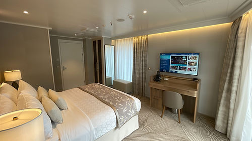 View from the doorway of the Enchanted Princess Sky Suite master bedroom featuring a vanity desk, flat-screen TV, and bathroom door.