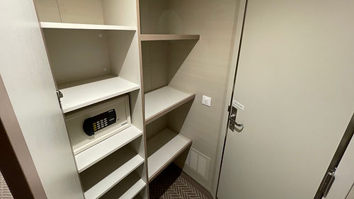 Multi-tiered open shelving unit providing storage space inside an interior cabin on Sky Princess.