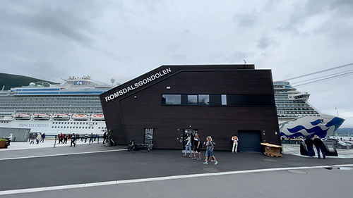 The Romsdalen Gondola station in Åndalsnes with Princess Cruises' Enchanted Princess docked in the port behind it.
