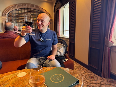 Dom from Tom and Dom Travel holding a large glass of red wine inside The Glass House bar and restaurant onboard P&O Cruises ship Ventura.