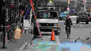 cyclist weaves around a commercial vehicle blocking a bike lane in new york city