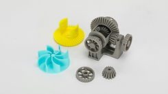 Various 3D printed mechanical parts in different colors on white background.
