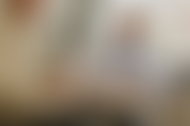 Paciente segurando documentos durante uma consulta com médico, que está sentado à mesa usando jaleco e estetoscópio, analisando papéis ao lado de um laptop em consultório iluminado.