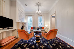 Boutique Vacation Rental Savannah living room with orange armchairs and stone fireplace by Savannah 