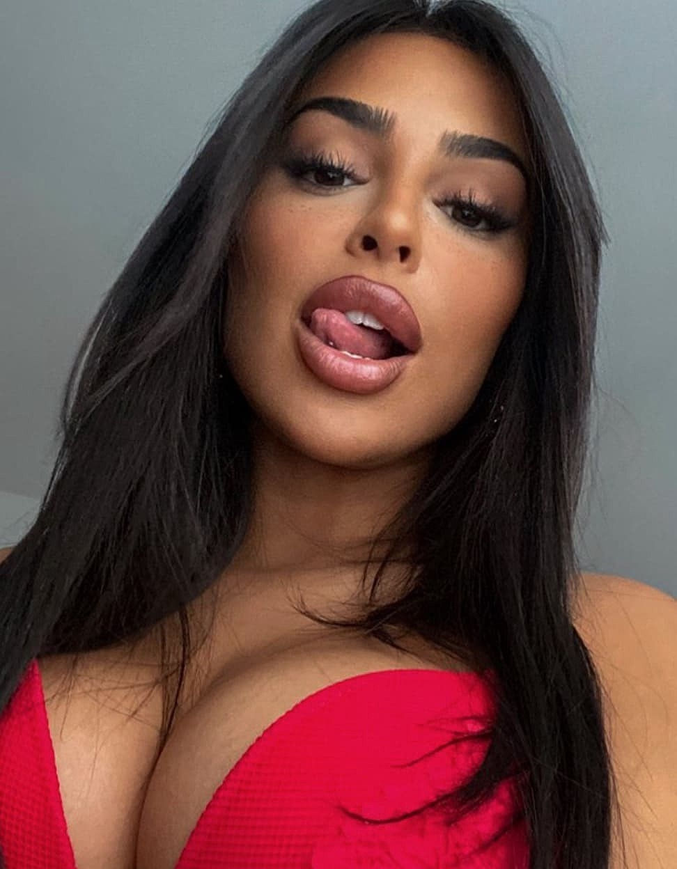 Das Bild zeigt Model Marys_Crib mit einem rotem Bikinioberteil. Der Mund ist leicht geöffnet und Mary streckt die Zunge heraus.