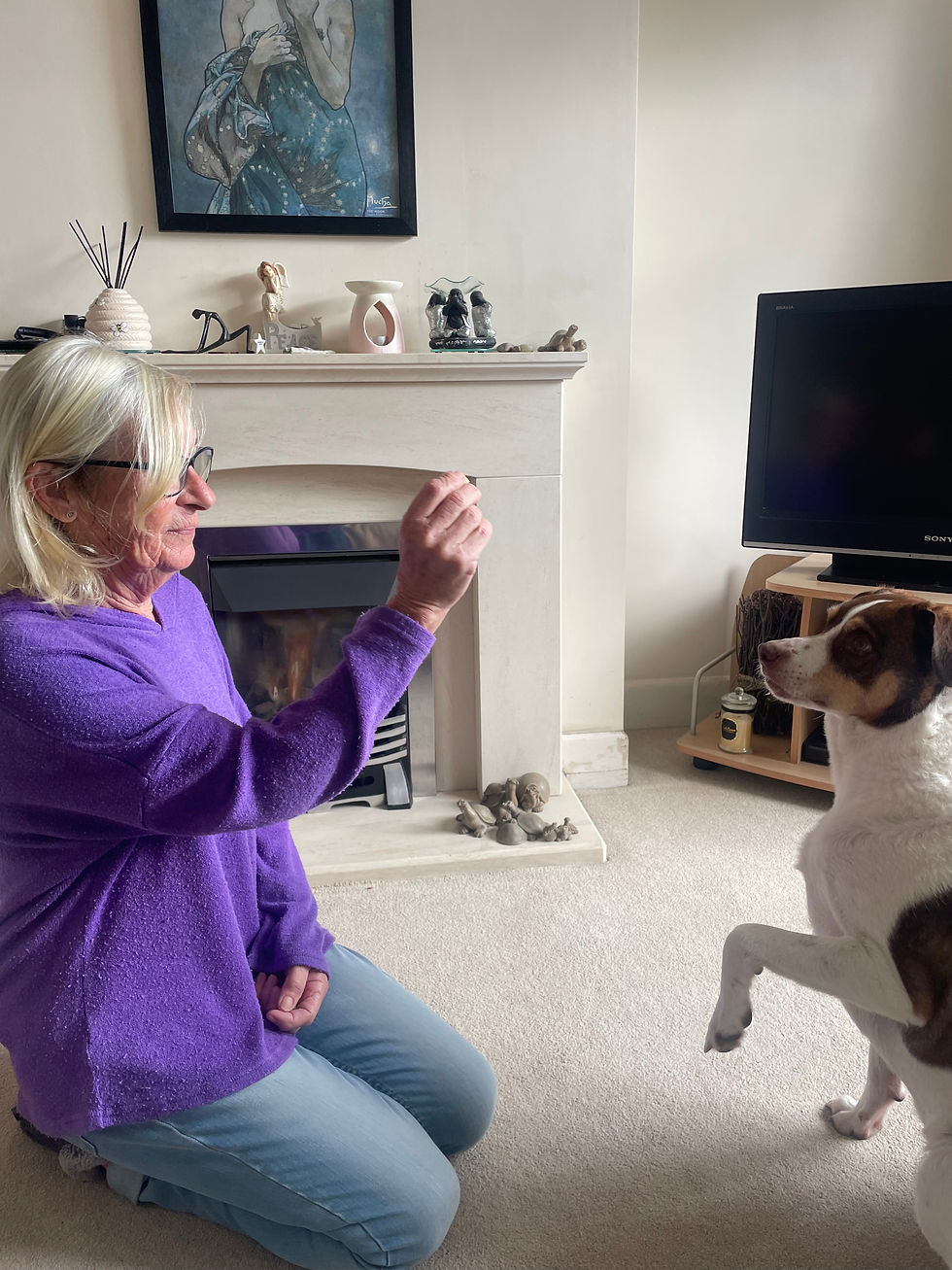 Jan Ryan with her dog, Dazzle, holding up a treat. (Sourced by Daisy Pearce)