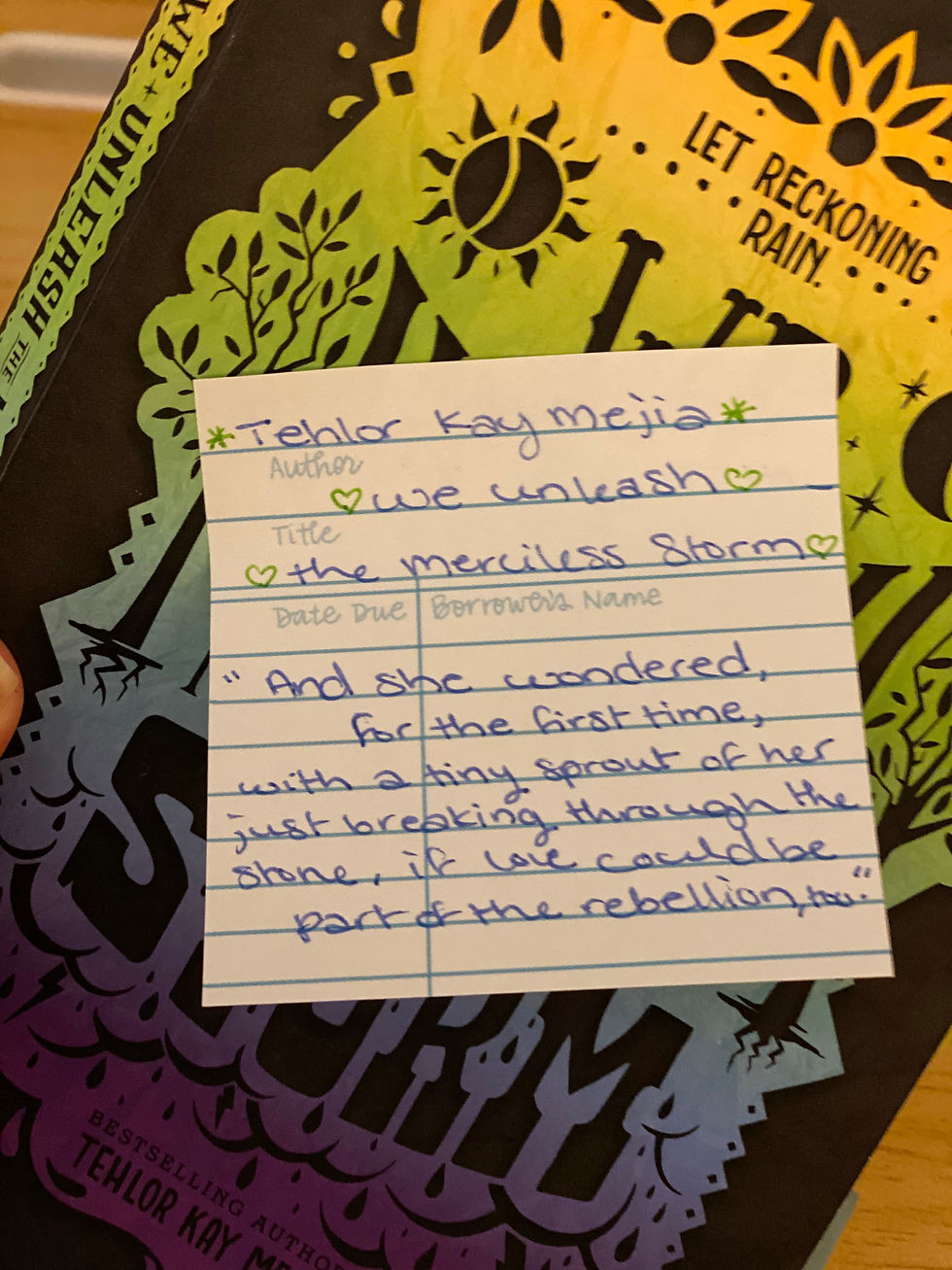 Book catalog sticky note with the following text: Tehlor Kay Mejia (author) We Unleash the Merciless Storm (title) "And she wondered, for the first time, with a tiny sprout of her just breaking through the stone, if love could be a part of the rebellion, too."