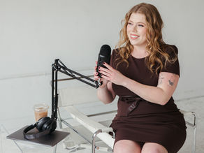 Hayleigh Hayhurst, founder of Espresso Podcast Production, wearing a brown dress with Microphone and Coffee