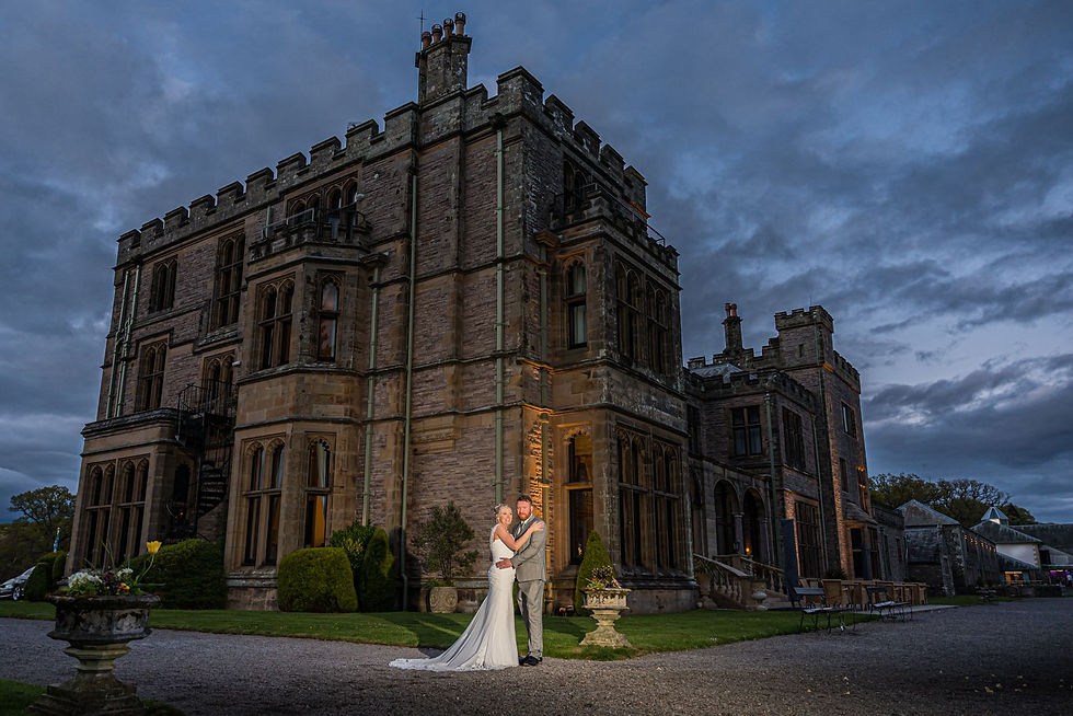 a wedding venue in the lake district, lit up at dusk with a happy married couple on their wedding day