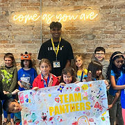 A lively group of kids proudly holding a Team Panthers banner, showcasing their team spirit and unity.