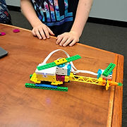 A young boy happily playing with a Lego helicopter, exploring endless possibilities!