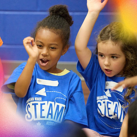 Two children in blue shirts and white pants sitting on a floor, engaged in an activity.