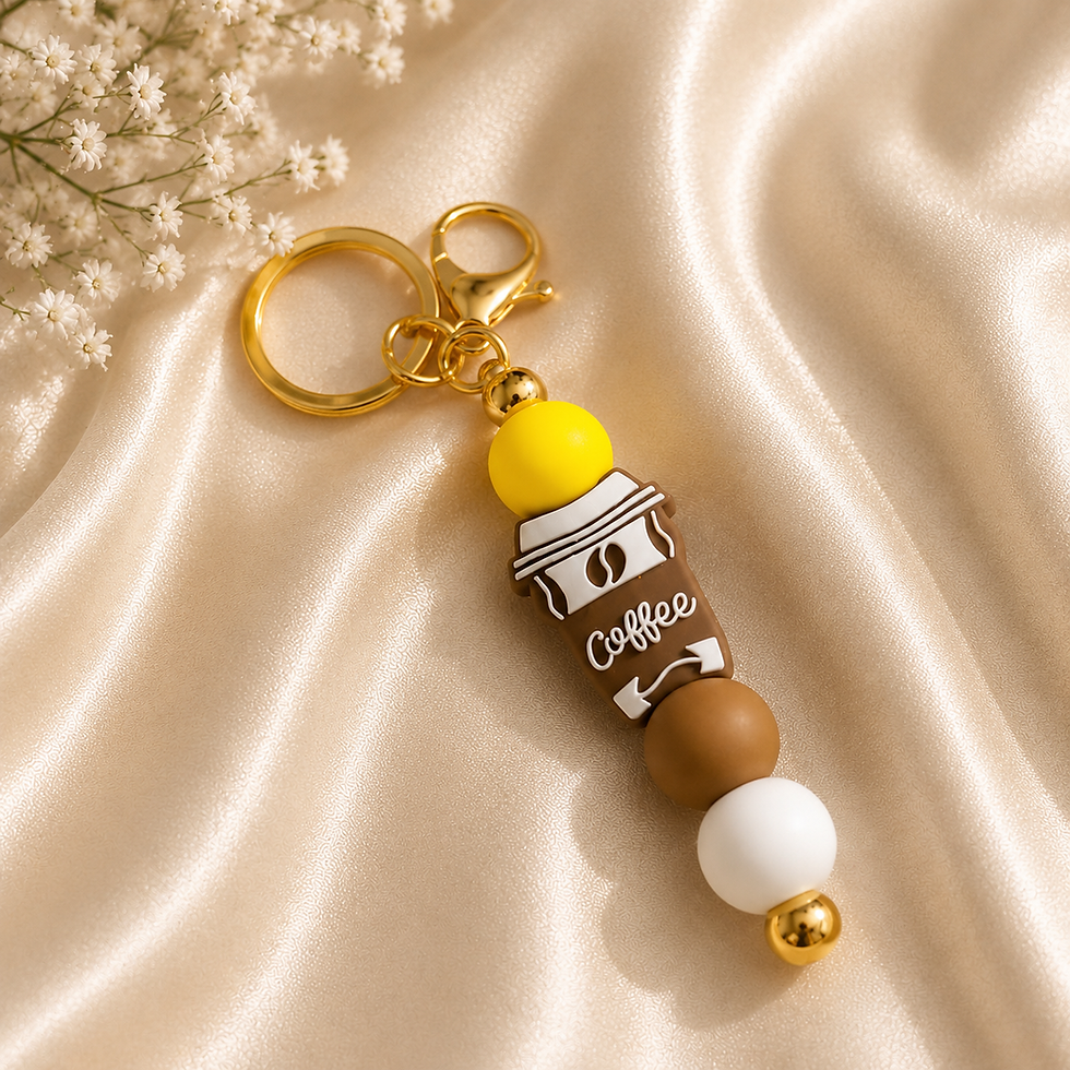Thumbnail: Handmade coffee cup beaded keychain with yellow, brown, and white silicone beads and gold hardware displayed on a cream silk
