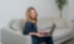 Seattle brand photography in studio of a woman sitting on a couch smiling with a computer