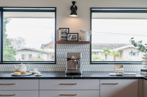 Kitchen with grey cabinets, white tile backsplash, and double windows