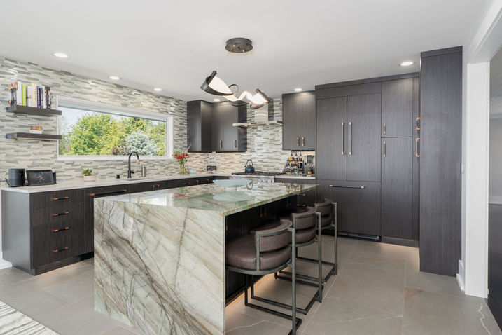 Kitchen with marble island, dark cabinetry, and pendant lighting