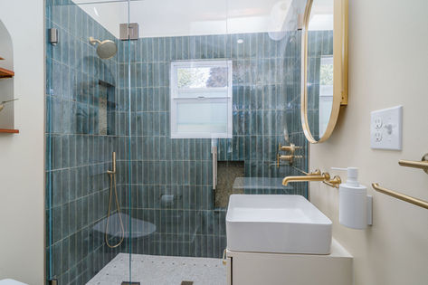 Bathroom with vertical blue tiles, small sink, and gold fixtures