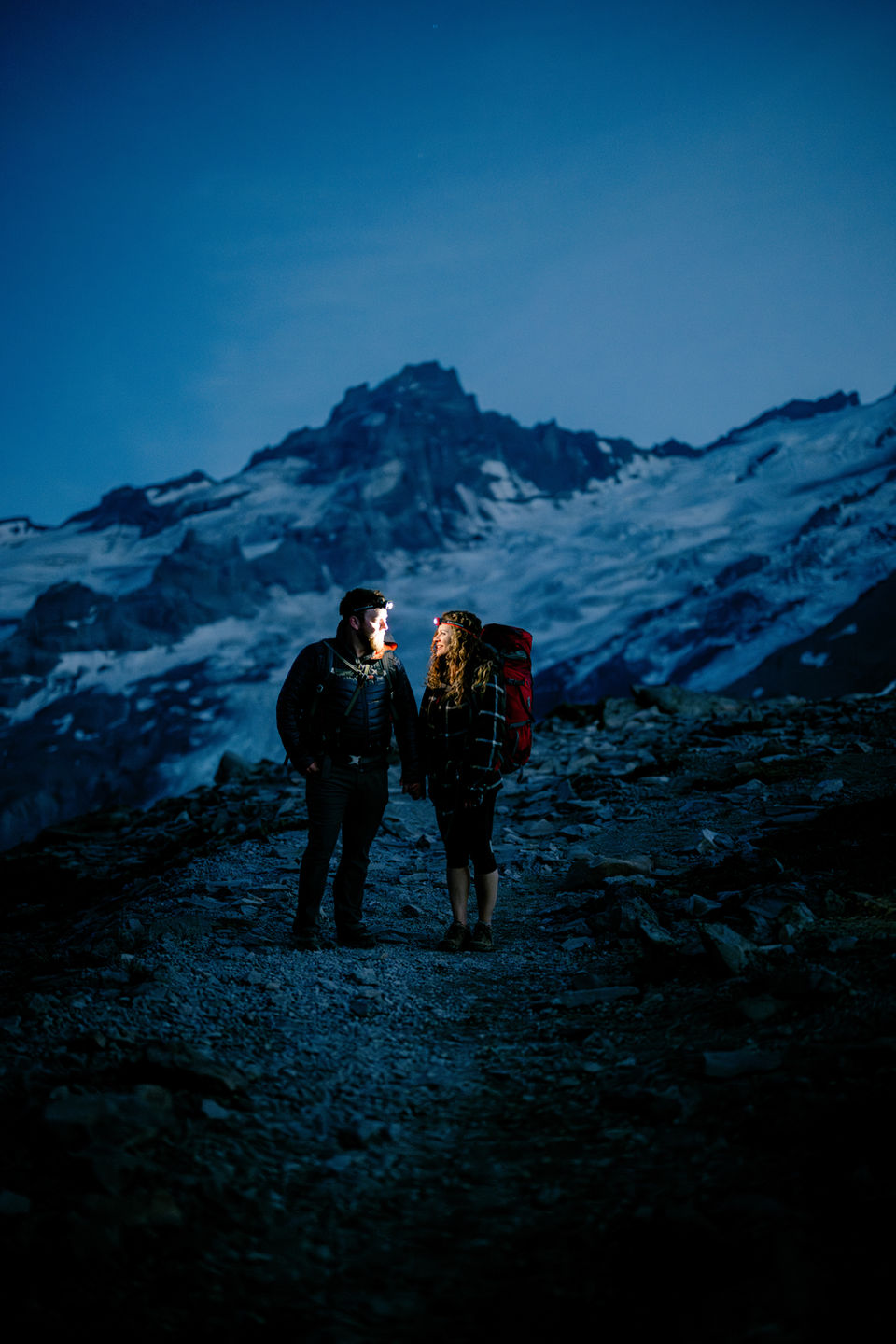 husband and wife hiking with headlamps at night