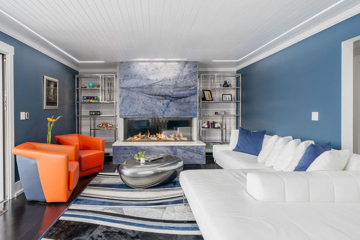 Living room with blue walls, fireplace, and bold furniture in Seattle residence