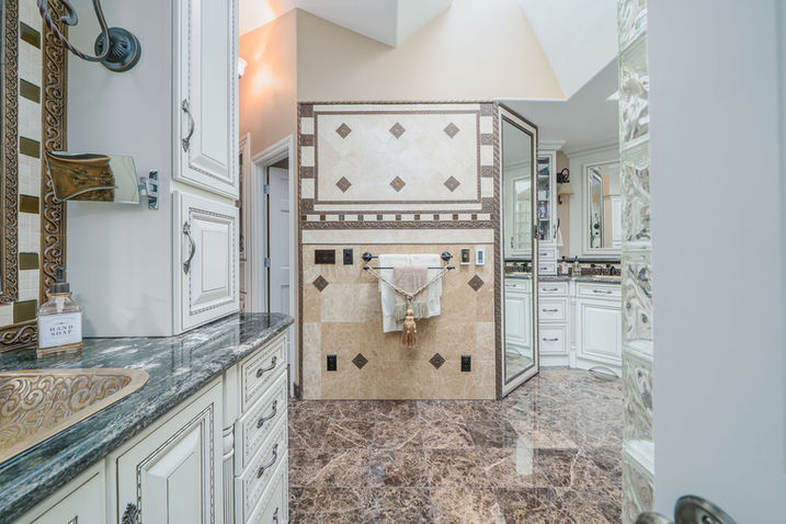 Luxurious bathroom with ornate cabinetry, marble flooring, and large shower