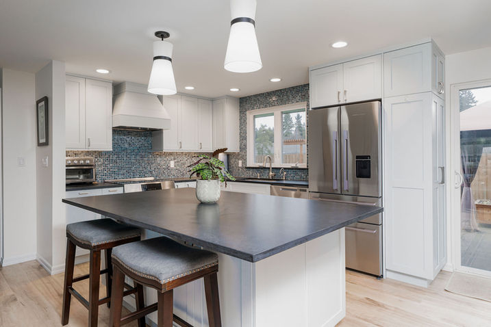 Kitchen with dark island, white cabinetry, and pendant lighting in Puget Sound home