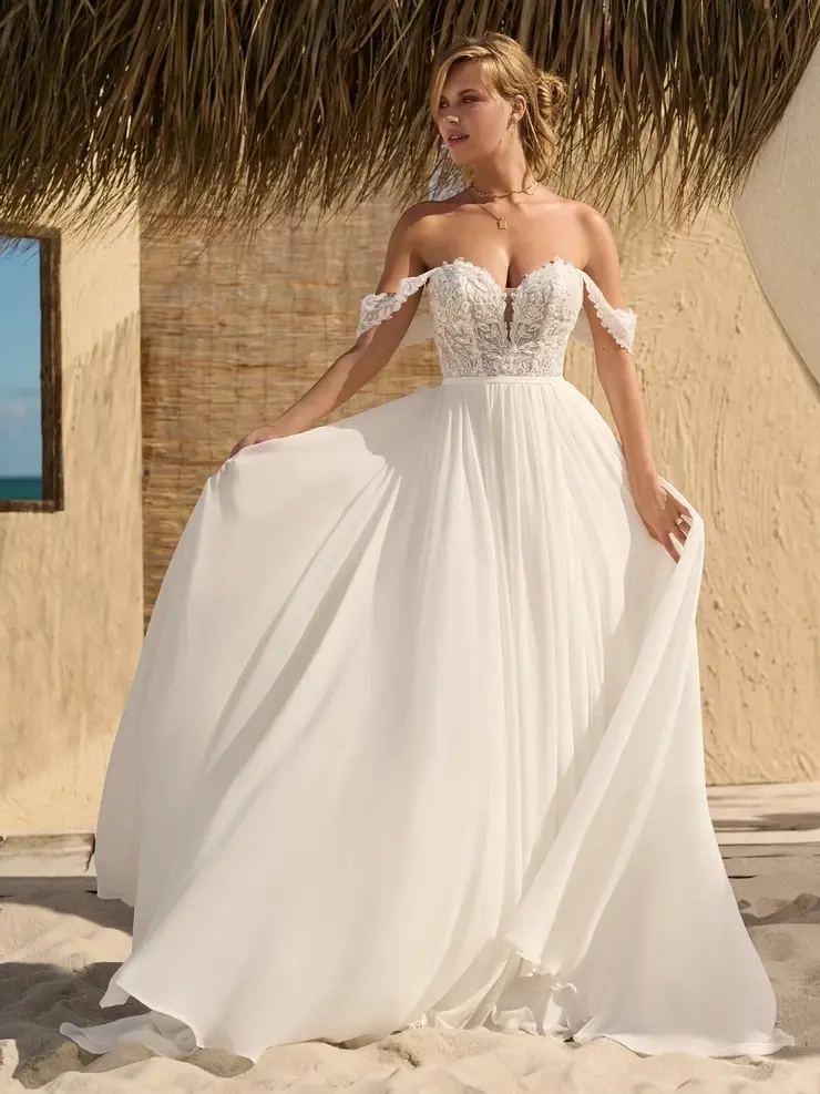 Woman in white off-shoulder wedding dress posing on sunny day.