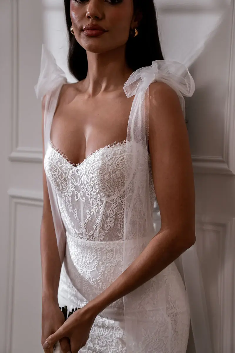 Thumbnail: Elegant woman in a lace wedding dress, Chosen by Khya, Orelle, standing indoors.