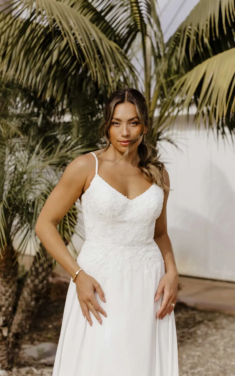 Thumbnail: Elegant woman in white wedding dress with palm trees in background.