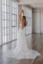 Thumbnail: Woman in a white wedding dress posing next to large windows.