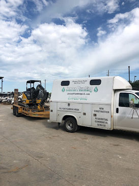 See Jensen Plumbing LLC's fully equipped truck, pulling a trailer with a backhoe, all set to provide efficient and reliable plumbing solutions wherever needed.