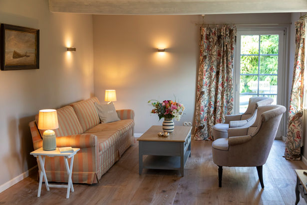 Gemütliche Wohnzimmer im Ferienhaus Fjord Cottage mit Kamin und Blick in den Garten.