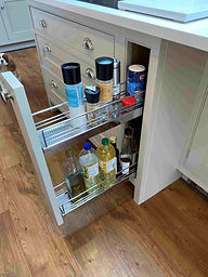 150mm pull-out storage unit neatly organising cooking oils, spices, and condiments beside a run of shaker drawers in a bespoke kitchen.