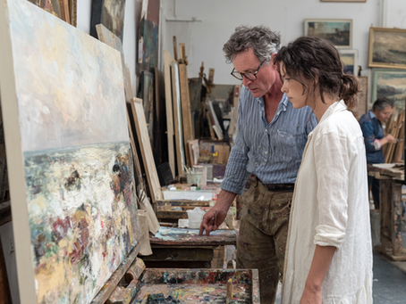 A collector an artist examining a painting on canvas