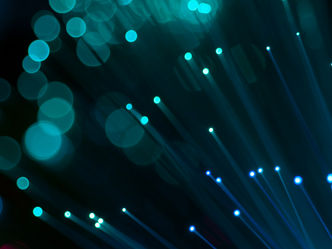 A radio tower and flock of birds in front of a sky during dusk