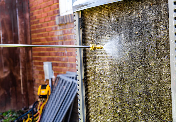 An HVAC technician cleaning an air conditioner. Rising a cooling unit with water in the sp