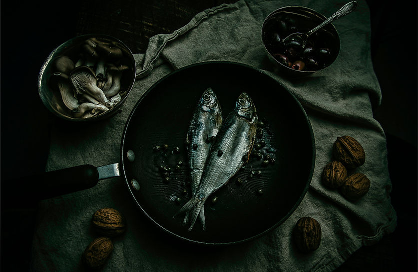 dark and moody, fish in a skillet, olives, mushrooms, and walnuts