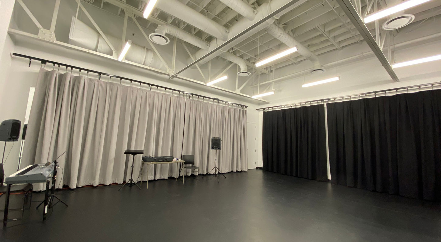 Interior view of a small rehearsal room within the Rehearsal Suite at Red Mountain Theatre. Acoustic curtains have been drawn across 2 of the walls.