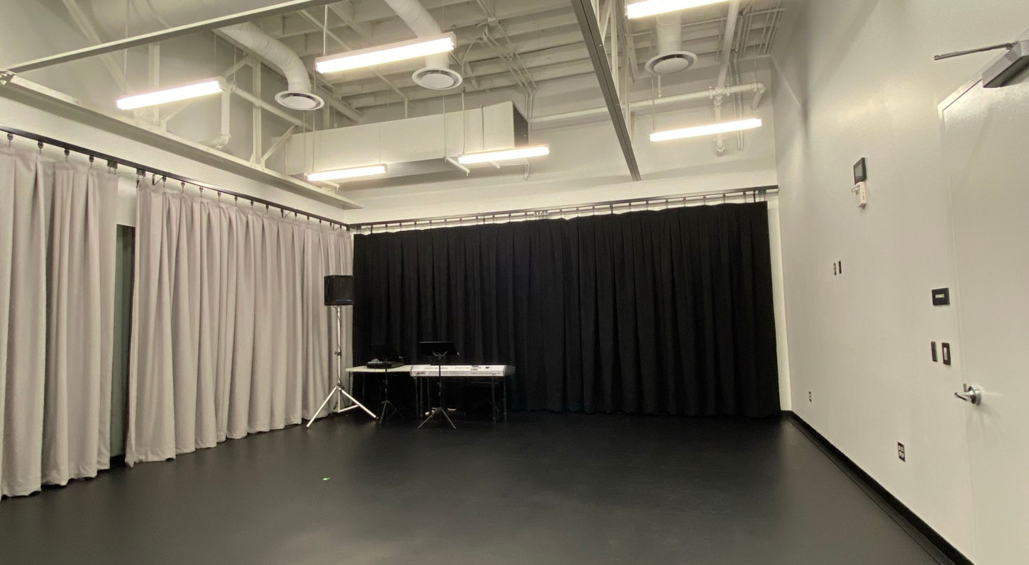 Interior view of a small rehearsal room within the Rehearsal Suite at Red Mountain Theatre. Acoustic curtains have been drawn across 2 of the walls.