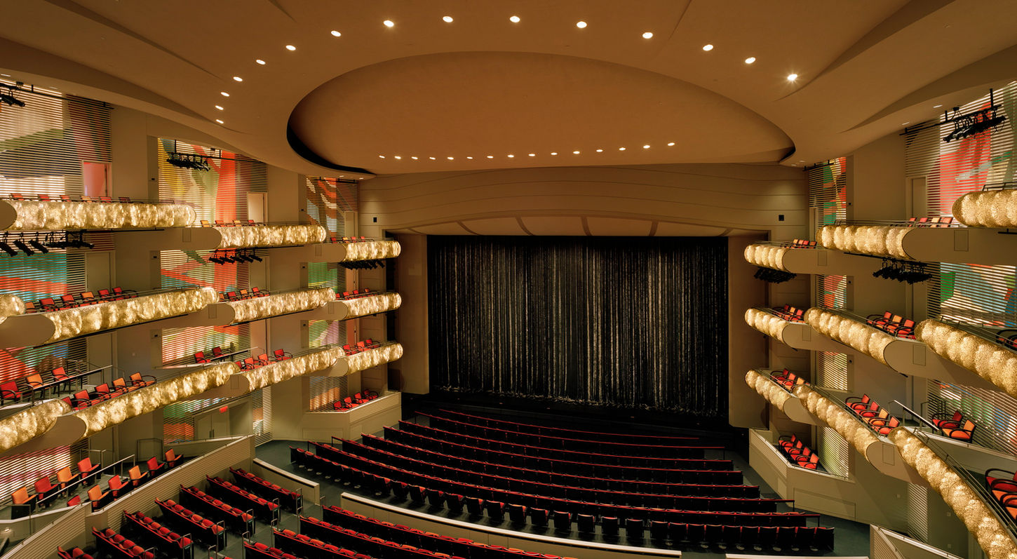 An interior view of Muriel Kauffman Theatre at the Kauffman Center for the Performing Arts. Looking from Rear Balcony Right towards the stage. The auditorium is empty, the LED balcony fronts are on display, and the stage curtain is drawn closed.