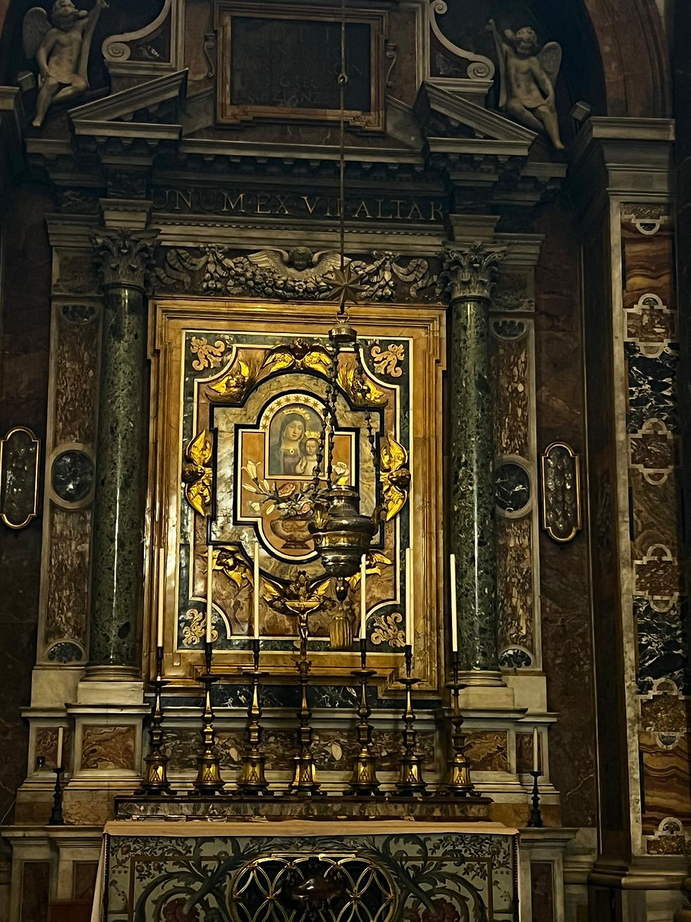 Ornate church altar with gold-framed Madonna icon, candles, marble columns, and Latin inscription above in a dim sanctuary.