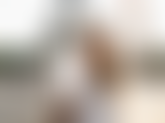 Woman in white holds phone showing aussieroam.com.au, smiles, raises arm, with Eiffel Tower in background, sunny day, joyful mood.