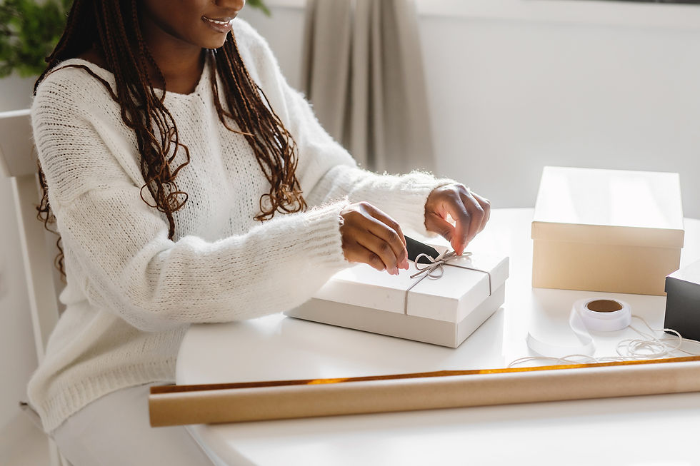 woman wrapping christmas gifts on a white table with holiday supplies