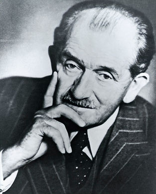 Historisches Schwarz-Weiß-Porträt von Ferdinand Porsche im Anzug, den Kopf nachdenklich auf eine Hand gestützt.