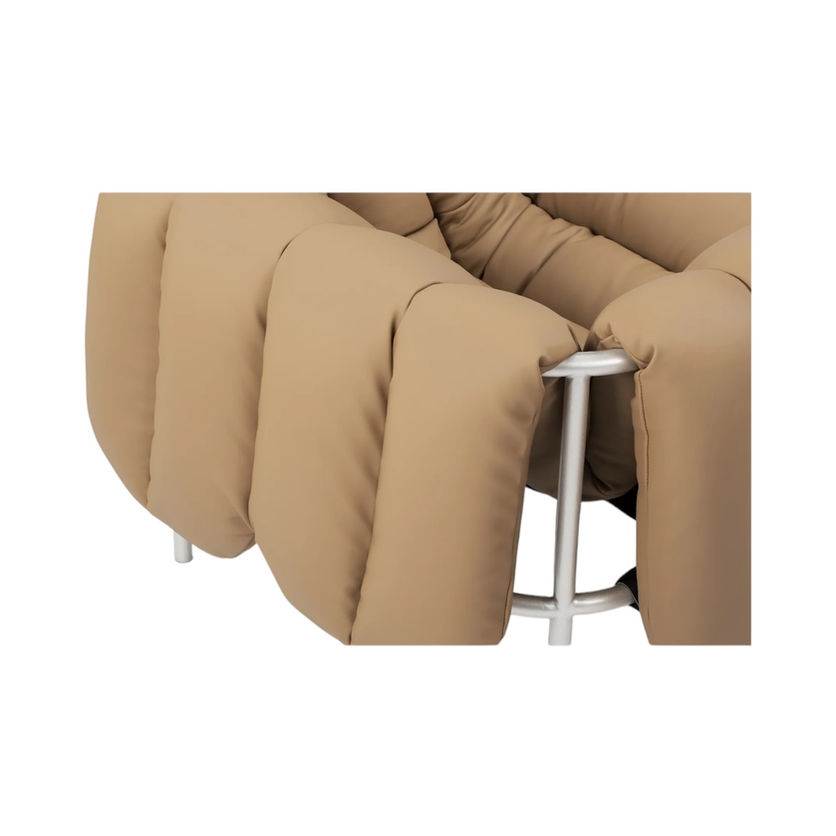 Close up of a tan, puffy armchair with silver metal frame