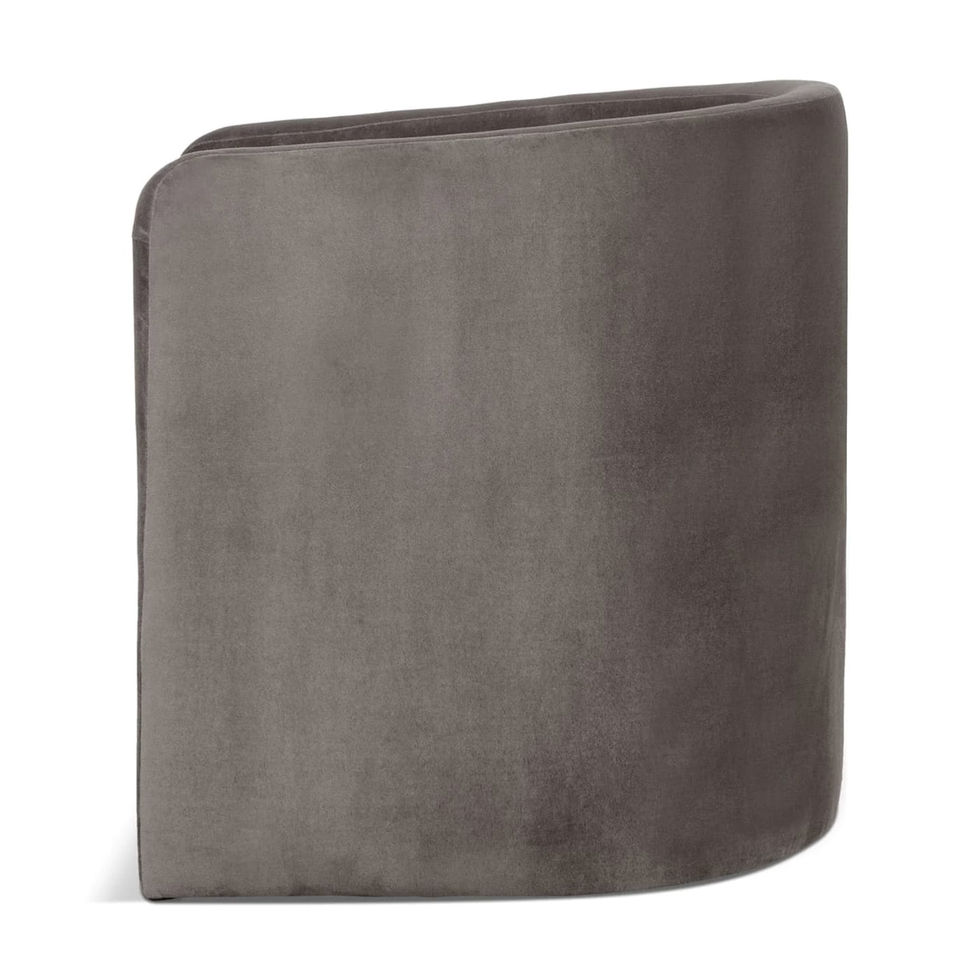 Gray velvet armchair with curved back, side view, isolated on white backdrop.